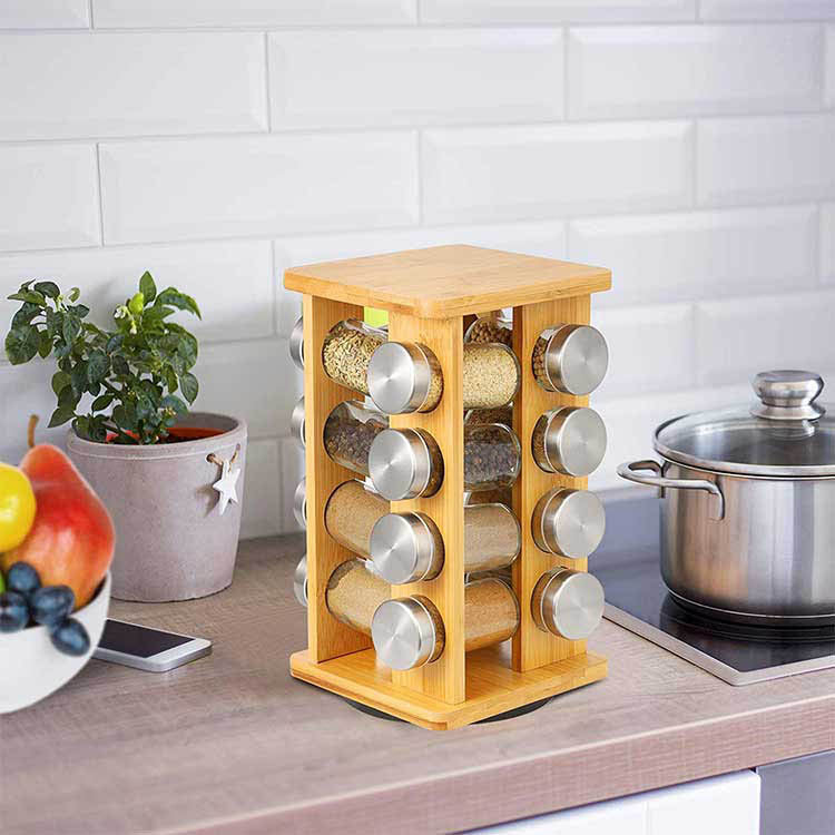 Bamboe draaibaar kruidenrek met zestien glazen potjes op een aanrecht in een moderne keuken, naast een pan en kruidenplant.