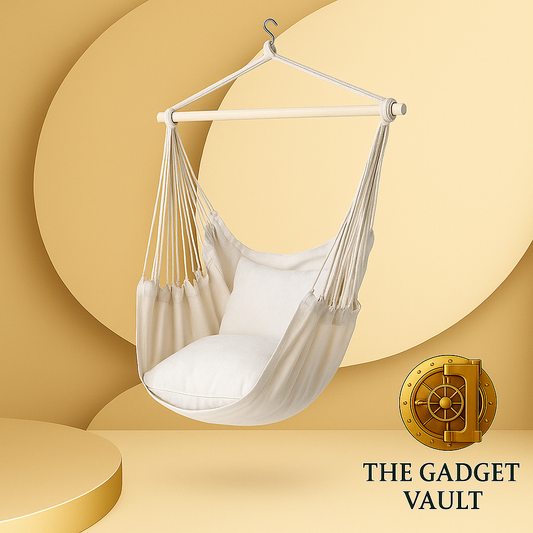Crèmekleurige hangstoel met houten spreidstok en twee zachte kussens, elegant gepresenteerd tegen een luxe beige-gouden achtergrond met het logo van The Gadget Vault rechtsonder.