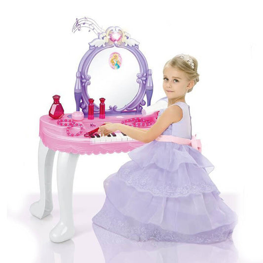 Klein meisje in prinsessenkleed speelt aan een roze speelgoed kaptafel met piano en spiegel – fantasierijk kinderspeelgoed voor rollenspellen.