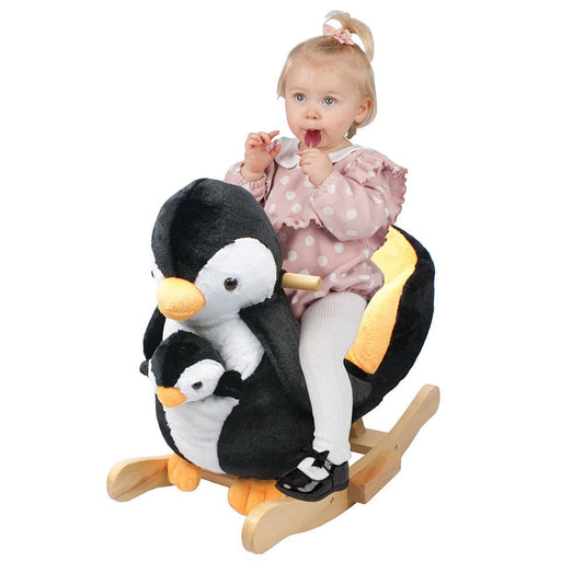Peutermeisje zit lachend op een pinguïn schommelstoel, omringd door zachte zwart-witte pluche en houten schommelbasis.